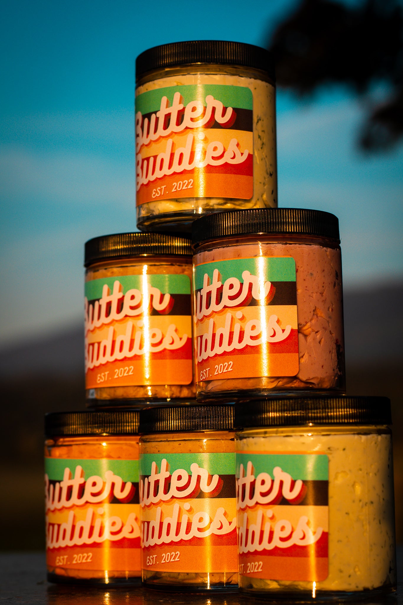 Pile of Butter Buddies flavoured butter stacked in a pyramid during sunset.