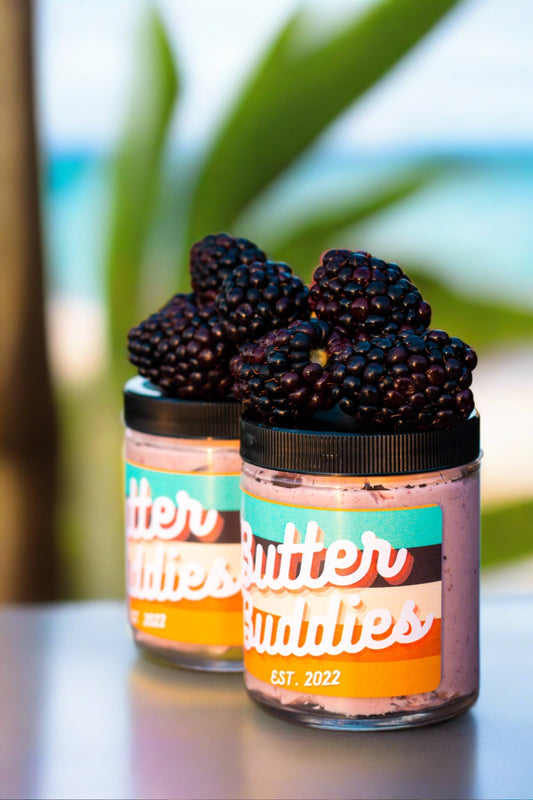 2 Jars of butter flavoured with blackberries, with blackberries piled on top. 