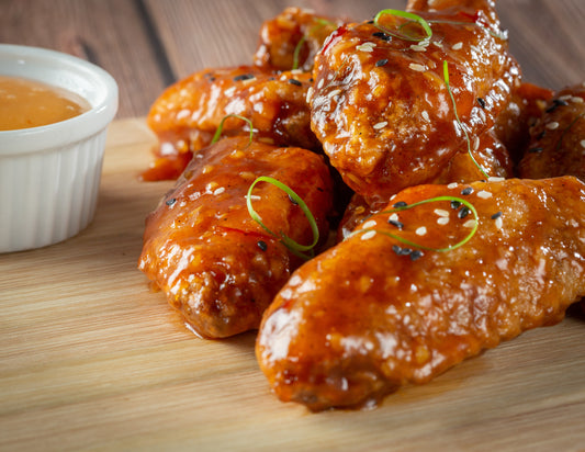 Sticky sweet and spicy chicken wings on a tray with sesame seeds